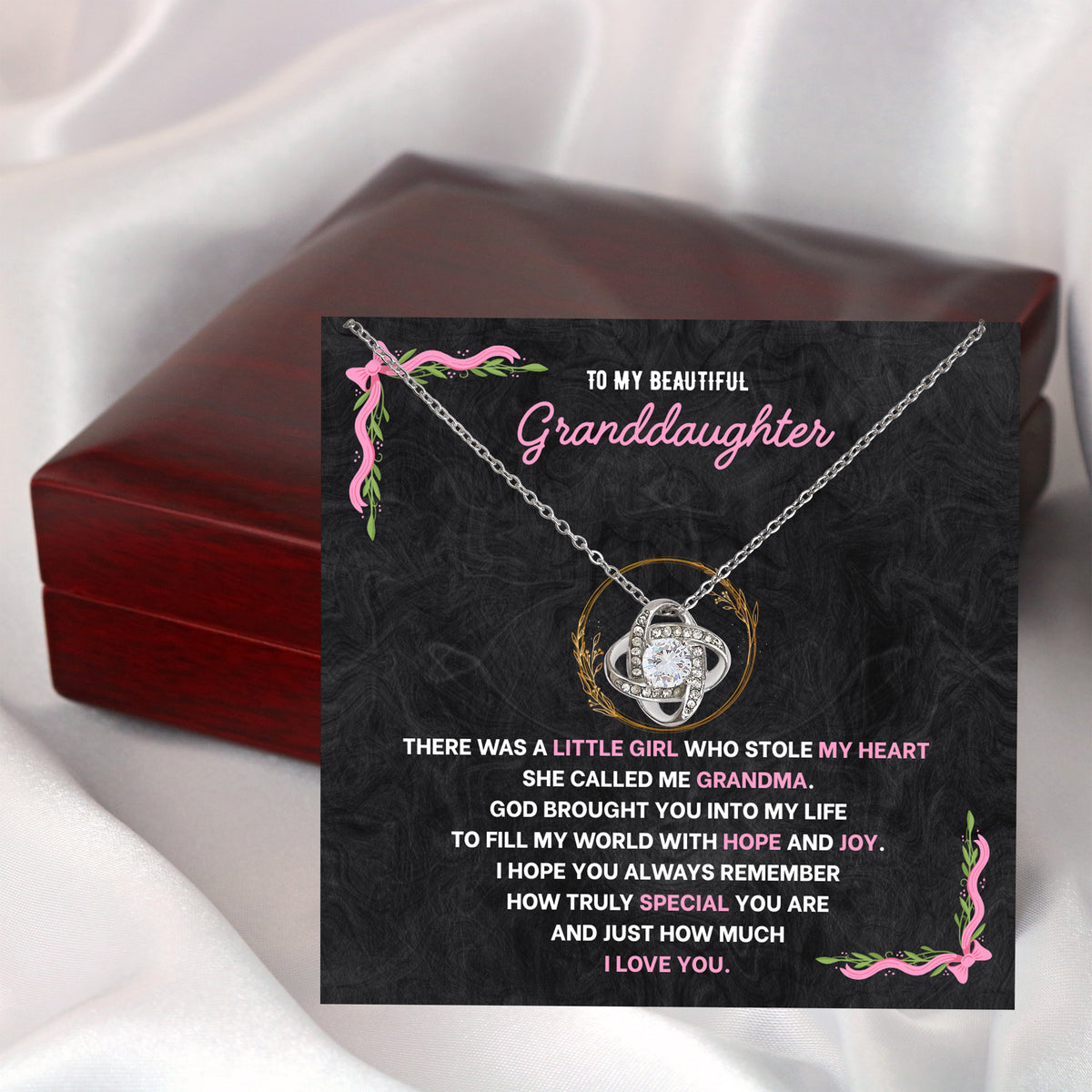 Wooden gift box beside a granddaughter necklace lying on its message card, on soft white satin