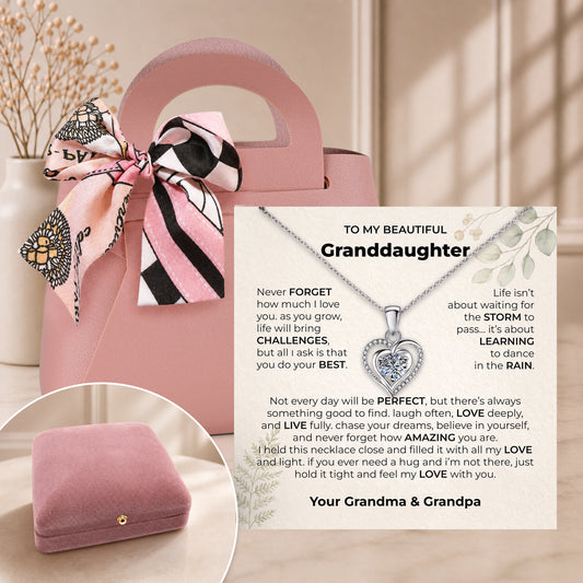 Pink gift bag with a scarf bow beside an open velvet box holding a granddaughter heart necklace and black card