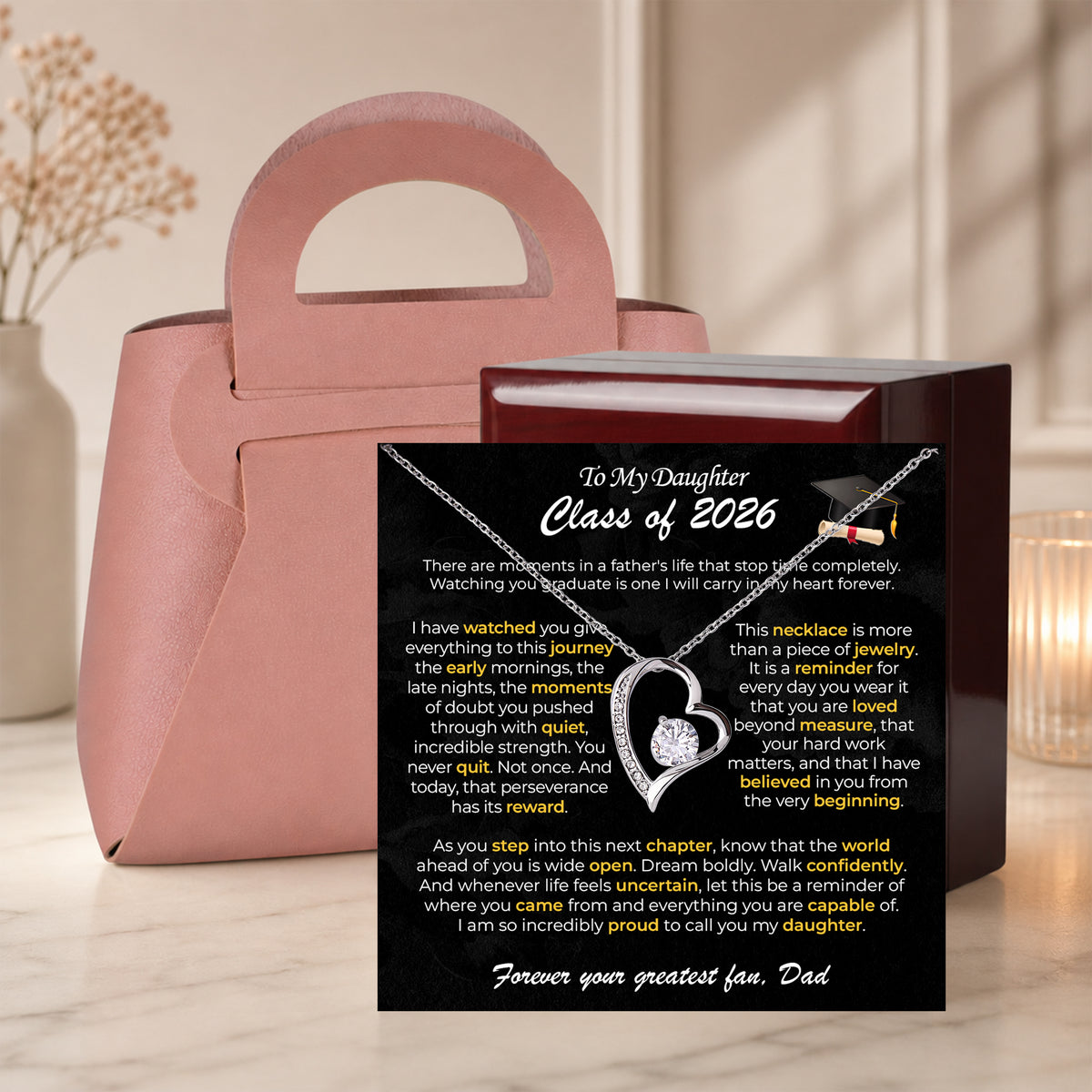 Gold heart necklace on a To My Daughter Class of 2026 graduation card inside an open pink gift box