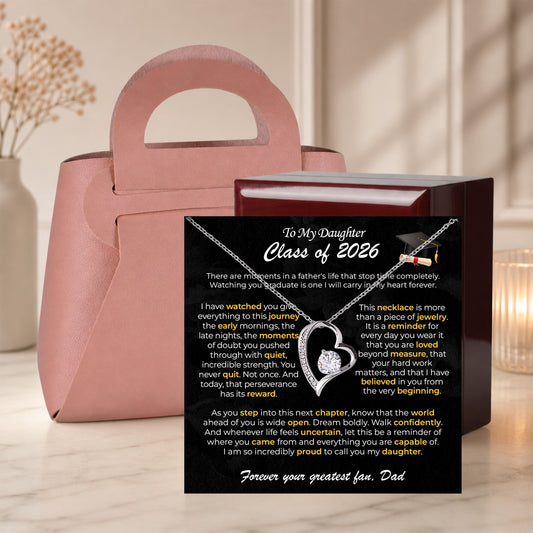 Gold heart necklace on a To My Daughter Class of 2026 graduation card inside an open pink gift box